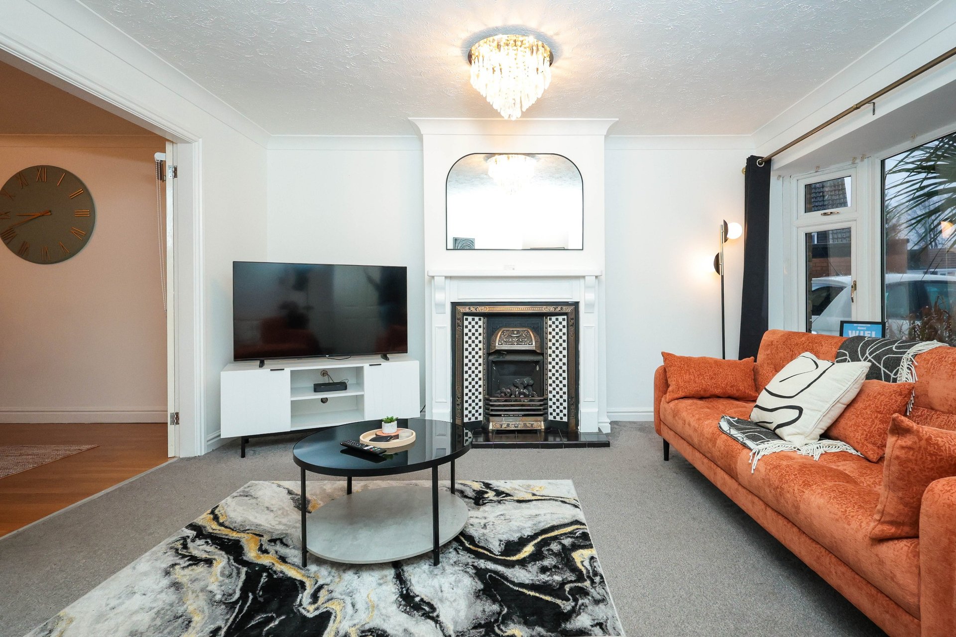 Modern living room with orange sofa, fireplace, TV, and wooden flooring