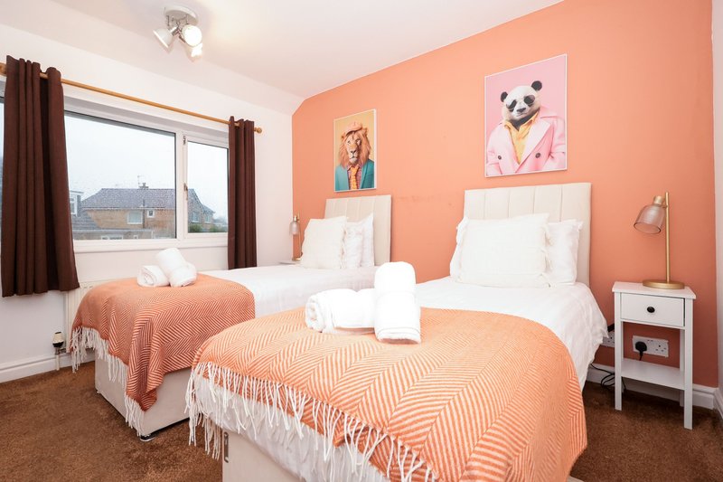 Bright twin bedroom with coral walls, white beds, framed dog artwork, and city view