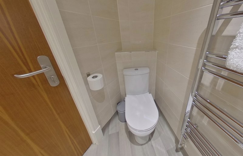 Small bathroom with toilet, towel rail, and cream tile walls