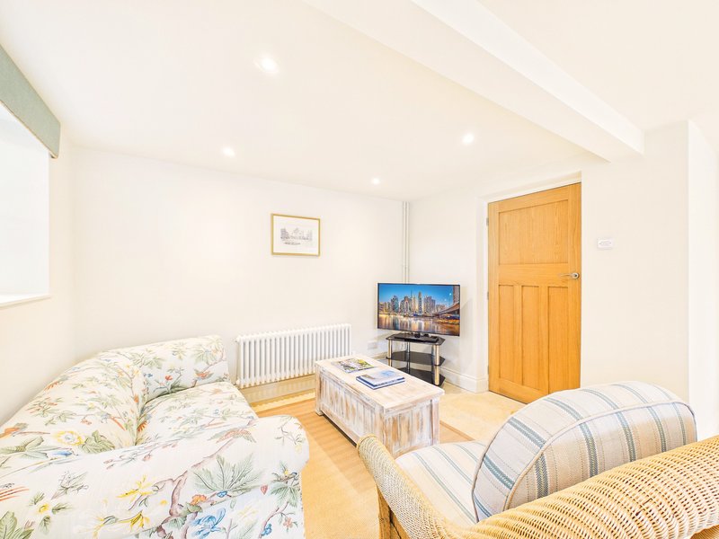 Bright bedroom with two beds, wooden floor, TV, and orange door
