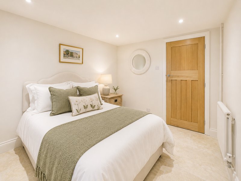 Bedroom with double bed, green bedding, wooden door, and bedside lamp