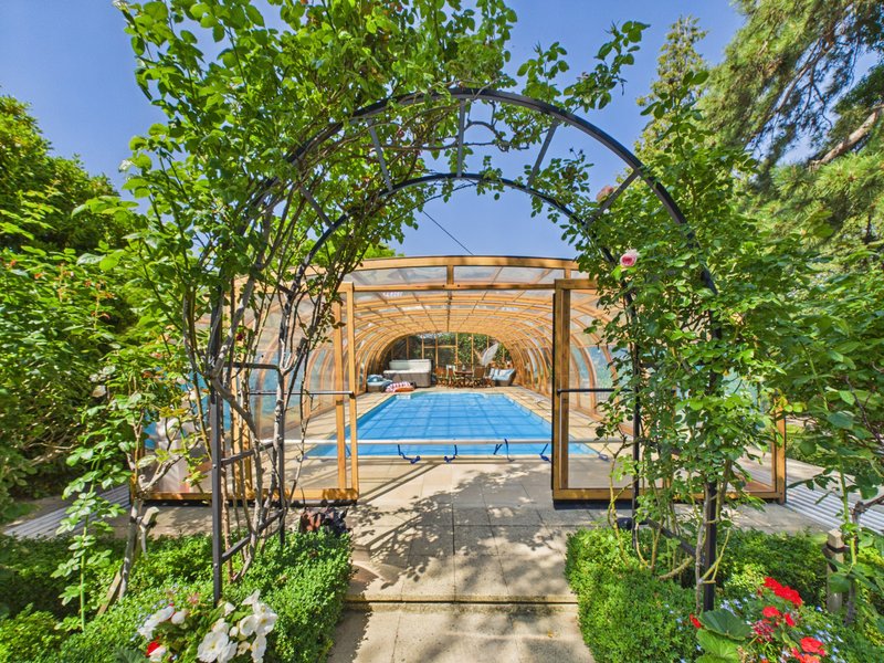 Garden arbor with ivy framing view of swimming pool and surrounding landscape