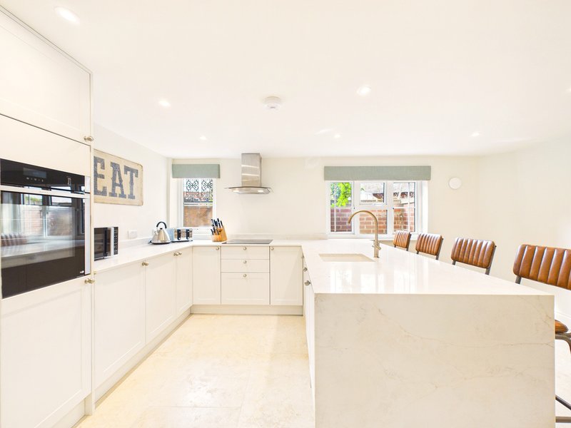 Modern kitchen with white cabinetry, island, and dining chairs overlooking garden