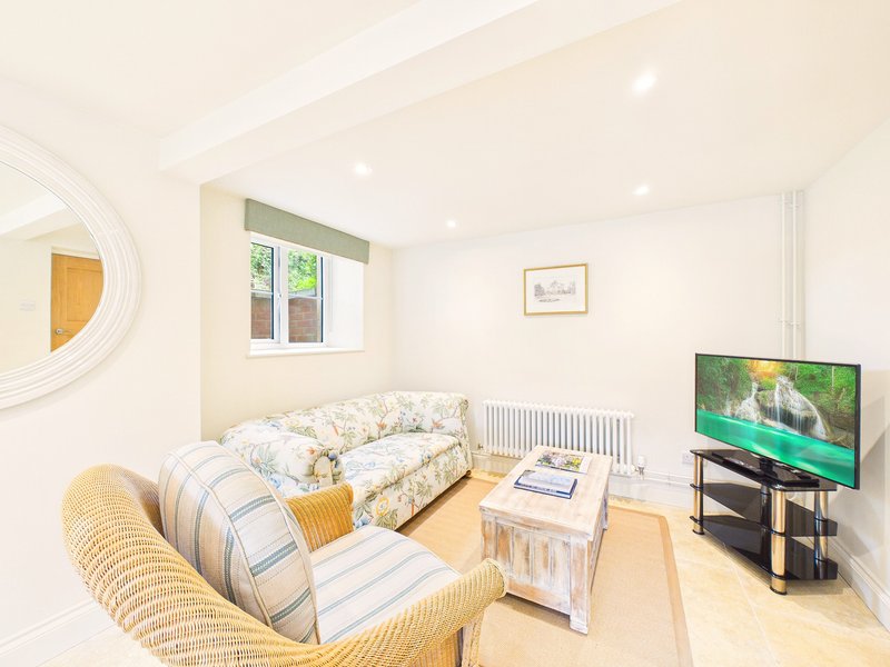 Living room with sofa, armchair, TV stand, and daybed with patterned bedding
