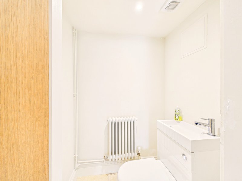 Clean modern bathroom with white sink, radiator, and wooden door frame