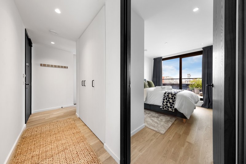 Modern bedroom with double bed, floor-to-ceiling windows, wooden flooring and hallway entry