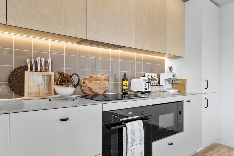 Modern kitchen with white cabinetry, gray countertop, black oven, and kitchen utensils and decor