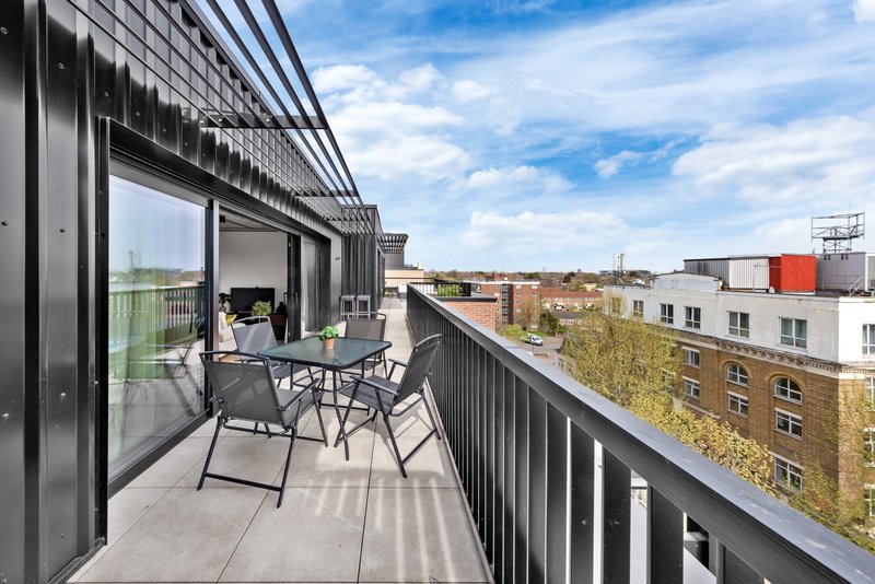 Modern balcony with dining table, chairs and city skyline view