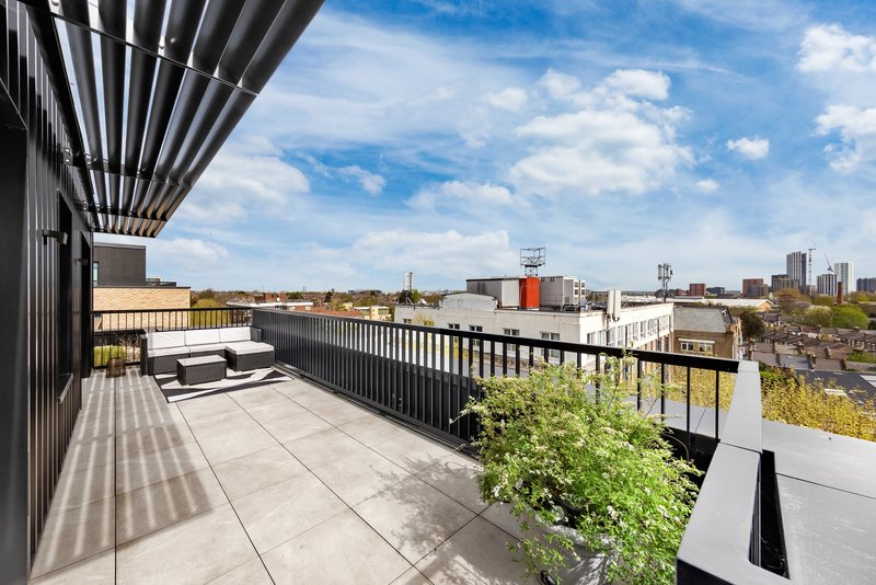 Rooftop terrace with seating, metal railing, and city skyline views