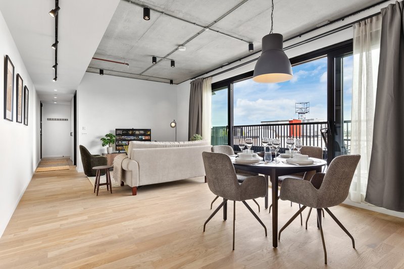 Modern open-plan apartment with dining table, sofa, and balcony with city views