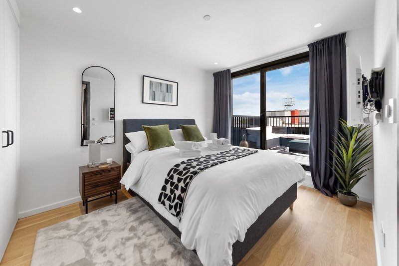 Modern bedroom with double bed, wooden nightstand, arched mirror, and balcony views