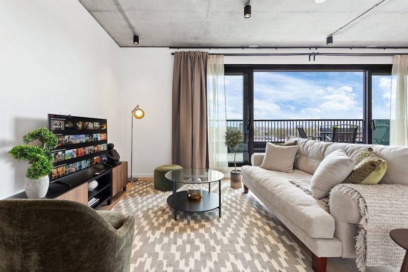 Modern living room with cream sofa, armchair, bookshelf, and balcony view