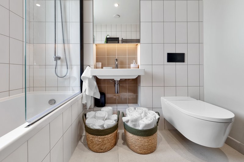 Modern bathroom with white tile walls, glass shower enclosure, wall-mounted sink and toilet