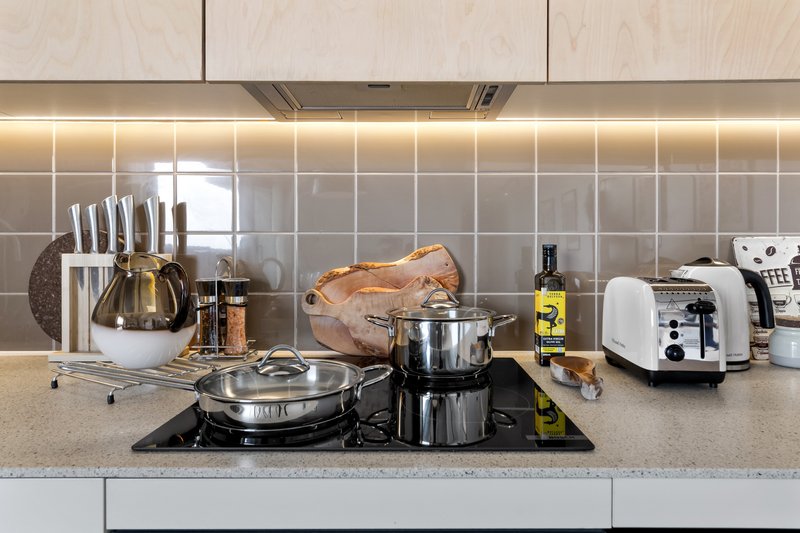 Modern kitchen countertop with cooking appliances, utensils, and everyday kitchen items
