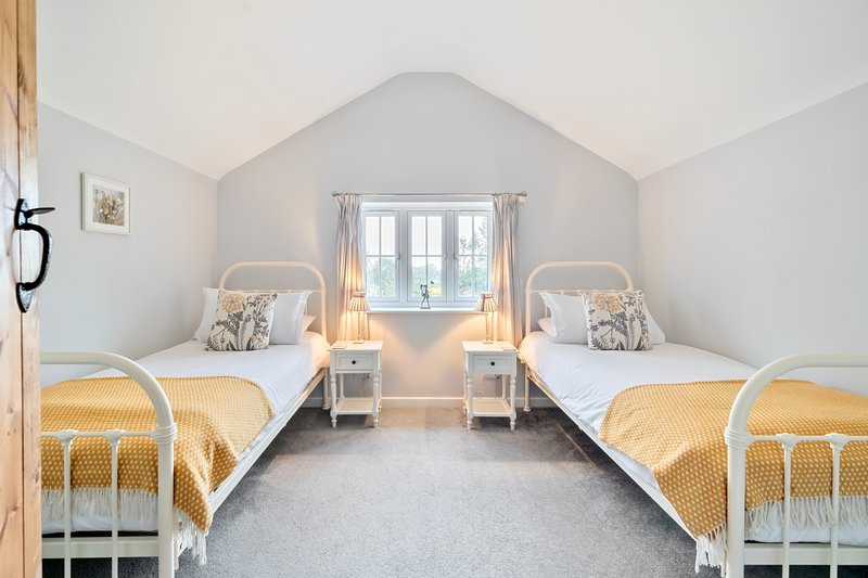Twin bedroom with two single beds, yellow bedding, white walls and sloped ceiling