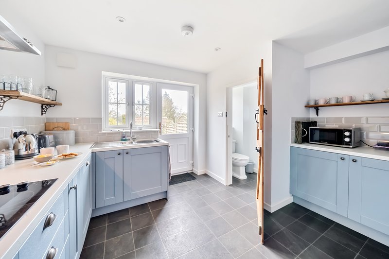 Modern kitchen with blue cabinetry, white countertops, and view to garden through patio doors