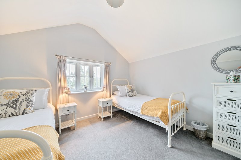 Bright bedroom with two single beds, white furniture, and sloped ceiling