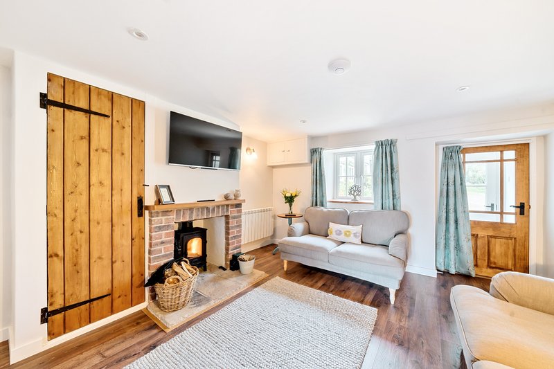 Bright living room with wood-burning stove, fireplace, cream sofa, wooden shutters and windows