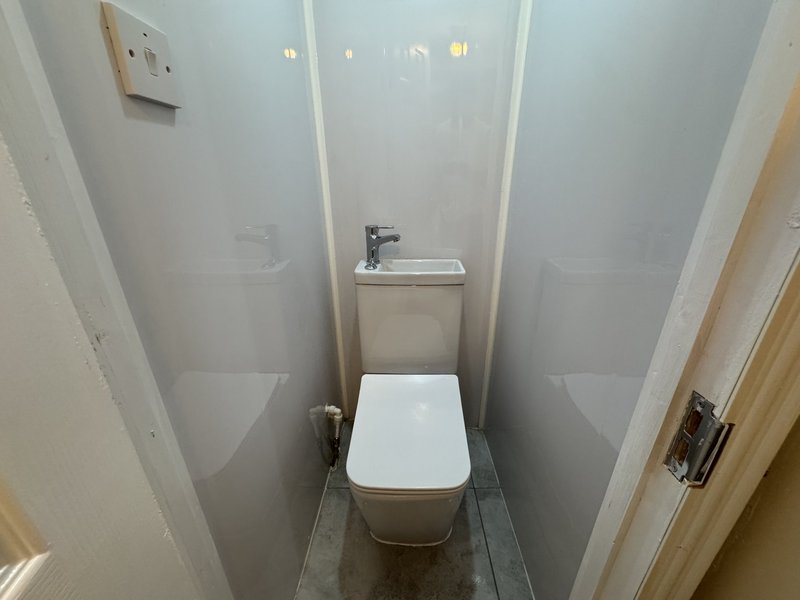 Compact bathroom with white toilet, small sink, and gray tile flooring
