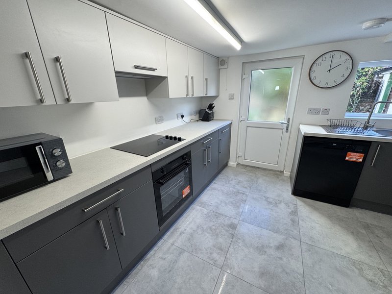 Modern kitchen with white and grey cabinetry, stainless steel appliances, white countertop and tiled flooring