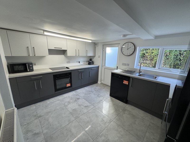 Modern kitchen with black and white cabinetry, grey tile flooring, and island seating
