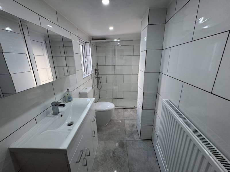 Modern bathroom with white vanity, toilet, walk-in shower and heated towel rail