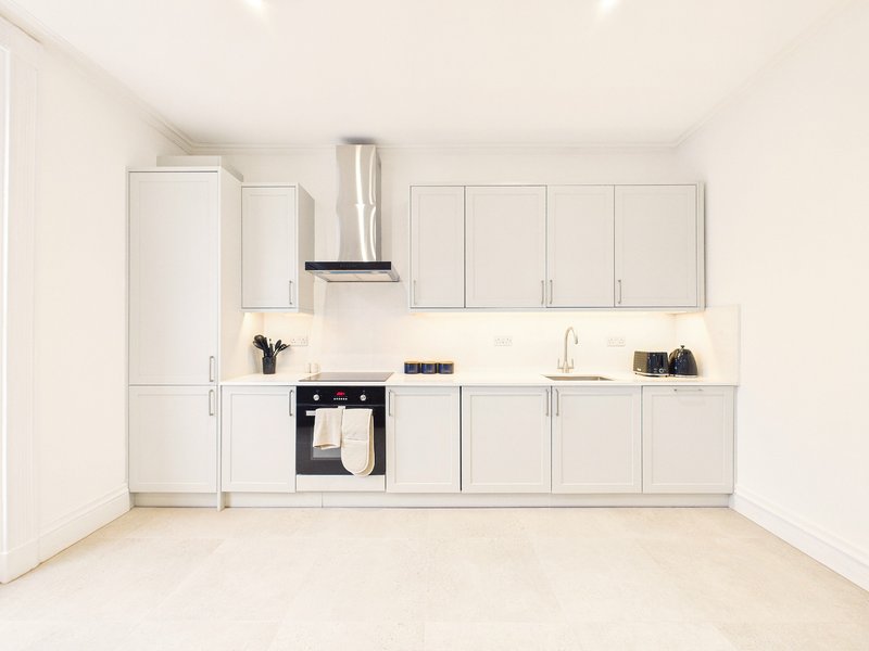 Modern white kitchen with fitted units, stainless steel appliances, and light flooring