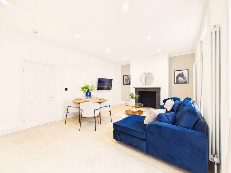 Modern living room with blue sofa, dining table, fireplace and wall art