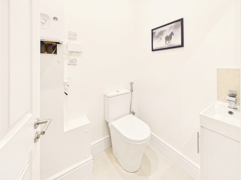 Clean white bathroom with toilet, sink, mirror and framed wall art