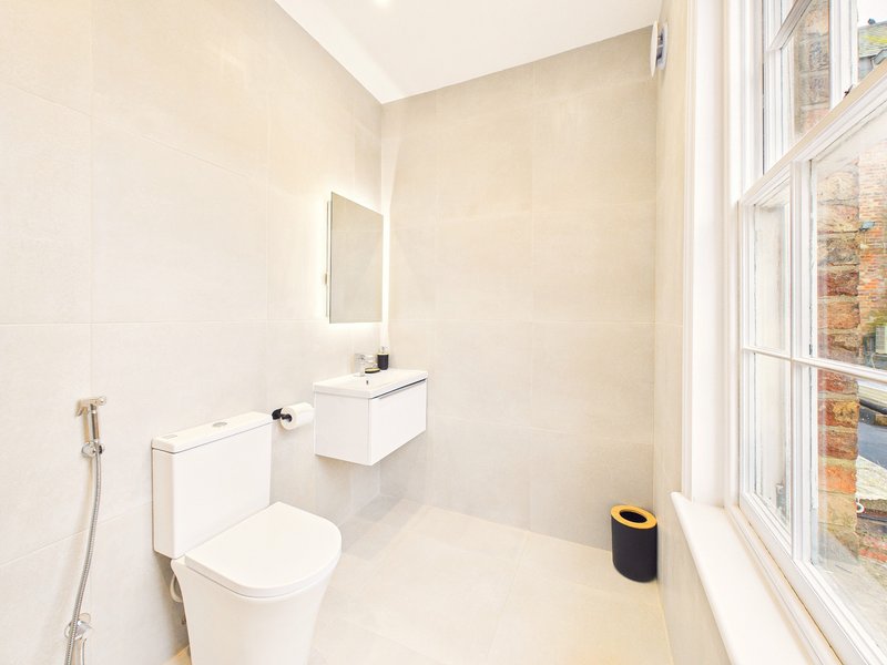 Modern bathroom with white vanity, toilet, mirror and window with natural light