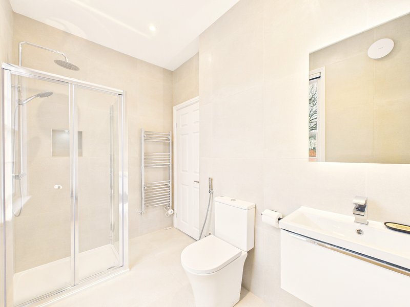 Modern bathroom with shower enclosure, toilet, white vanity sink and heated towel rail