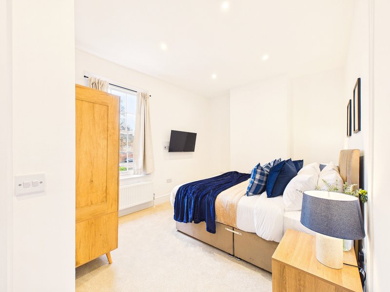Bright modern bedroom with double bed, wooden wardrobe, bedside table and window