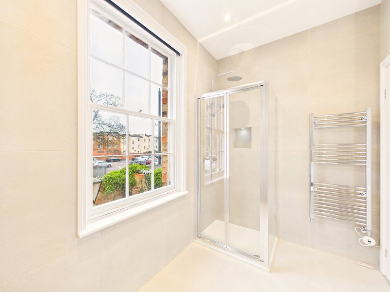 Modern bathroom with shower enclosure, heated towel rail, and window with garden view