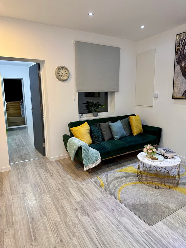 Modern living room with dark sofa, yellow and blue cushions, fireplace, and wood flooring