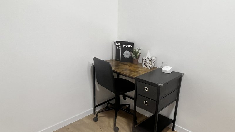 Corner desk with black chair, wooden top, storage drawers and desk accessories