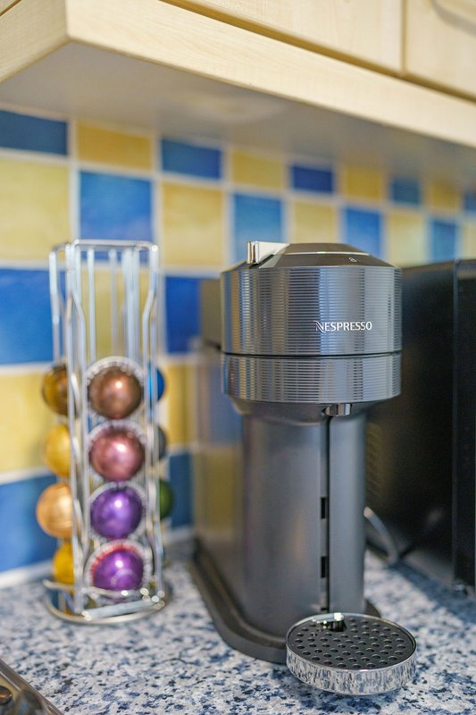 Kitchen counter with Nespresso coffee machine and capsule holder against colorful blue and yellow tiled backsplash