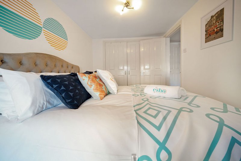 Bright bedroom with double bed, patterned bedding, decorative pillows and wall art