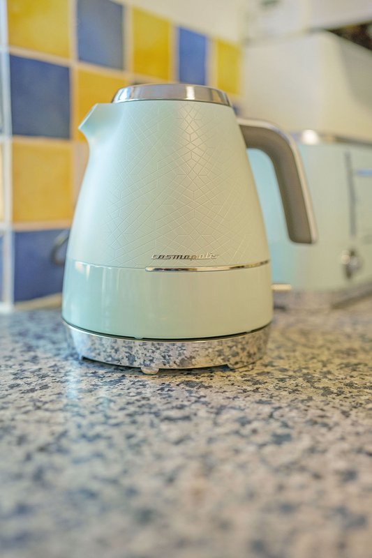 White electric kettle on kitchen counter with colorful tile backsplash