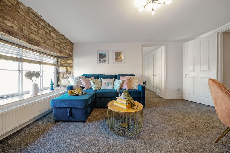 Spacious living room with blue corner sofa, gold side table, stone accent wall and large window