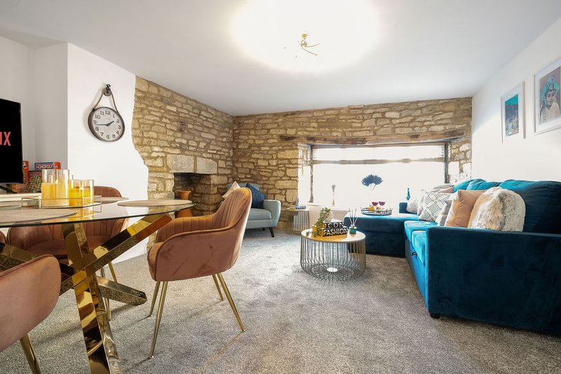 Open-plan living room with dining table, blue sofa, stone fireplace and large window