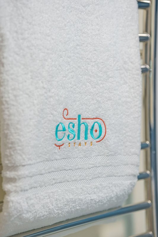 White towel with embroidered logo on shelf in bathroom