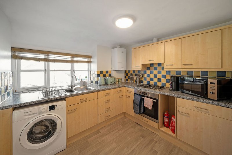 Modern kitchen with wooden cabinets, granite countertop, integrated appliances and tiled backsplash
