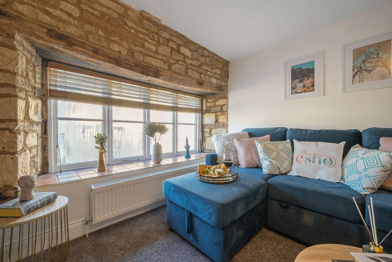 Modern living room with blue corner sofa, stone window surround, and framed wall art