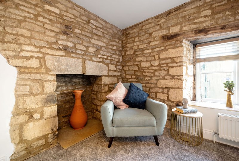 Cozy living room with stone fireplace, beige armchair, and window with natural light