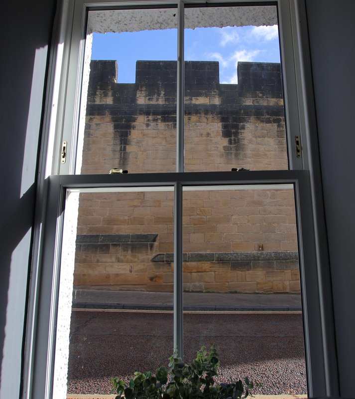 Window view of stone building exterior with courtyard and blue sky