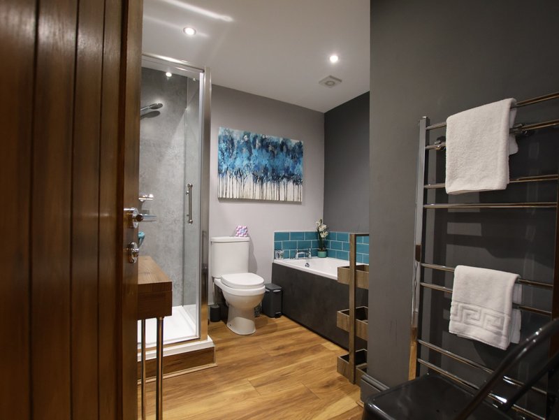 Modern bathroom with shower enclosure, toilet, vanity sink, heated towel rail and blue artwork