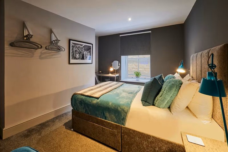 Modern bedroom with double bed, green bedding, pendant lights, and large window with countryside view