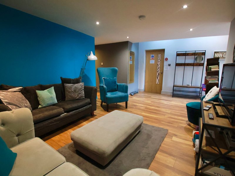 Modern open-plan living room with blue accent wall, dark sofa, wooden flooring and contemporary furnishings