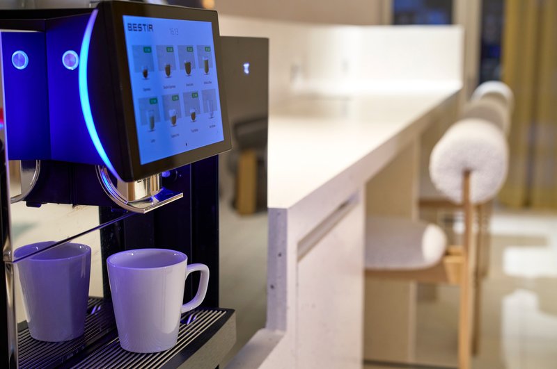 Modern kitchen counter with automatic coffee machine and two white mugs