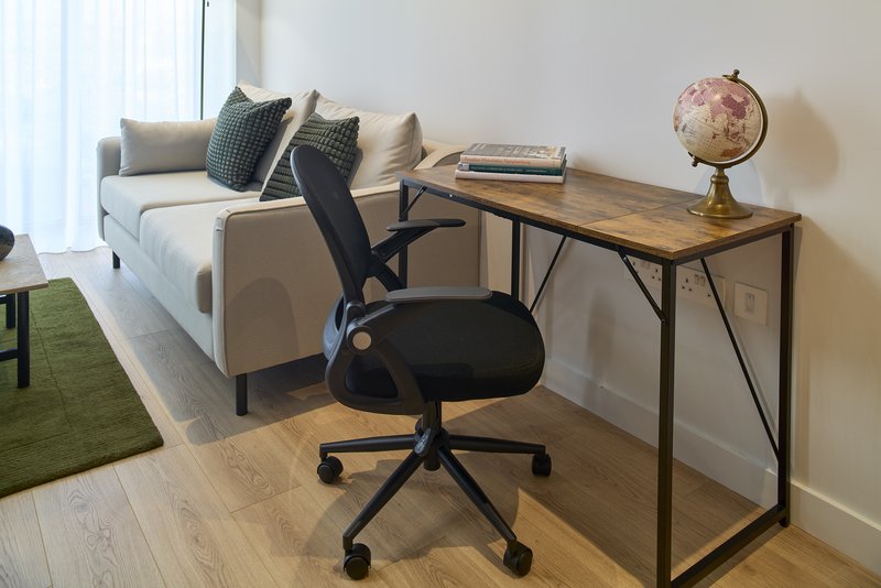 Studio workspace with desk, office chair, sofa, globe and cushions